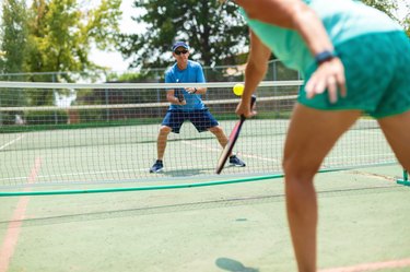 Mature Adult Couple Playing Pickleball on a Bright Summer Day after doing a pickleball warmup