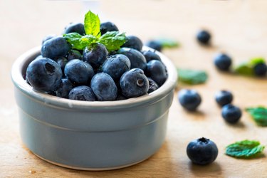 Cup of fresh blueberries to support healthy aging on wooden table