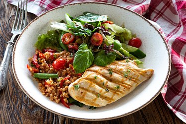 close-up image of a plate of chicken breast with a salad and whole-grain side