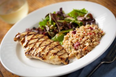 A close up of a healthy meal of quinoa, salad and chicken breast on a white plate for a weight-loss plan for men