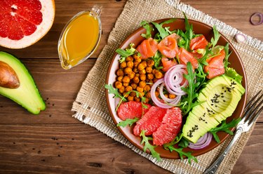 Healthy salad bowl with salmon, grapefruit, spicy chickpeas, avocado, red onion and arugula