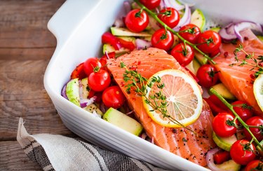 raw salmon with tomatoes, onion and lemon in white casserole dish