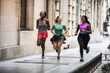 Group of friends running in city and chatting happily