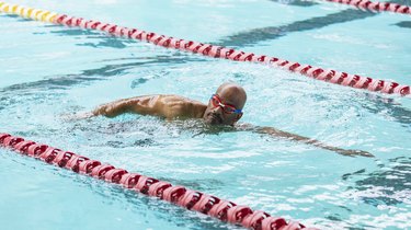 Person with psoriasis swimming laps in pool.