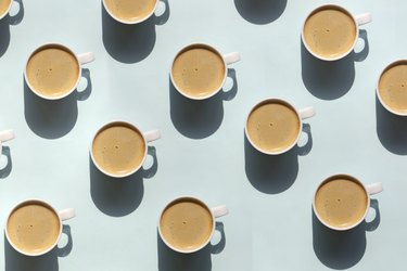 pattern made of mugs of coffee on light blue background