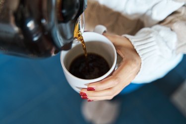 Person pouring herself hot coffee to a mug, a great drink for longevity