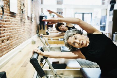 People working out on Pilates reformers in a Pilates studio.