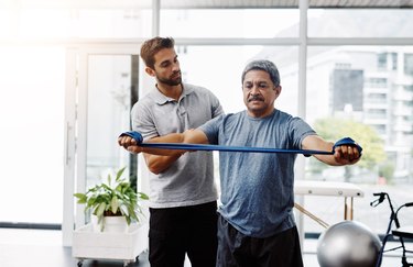 Person working out with resistance band with physical therapist.