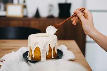 Woman's hand decorating cake with white chocolate