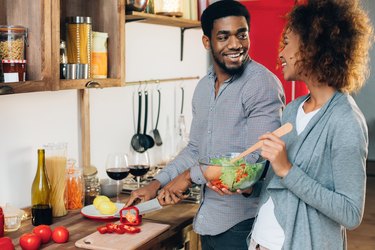 Couple chopping vegetables and making salad in kitchen