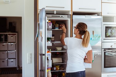 woman storing canned food in fridge