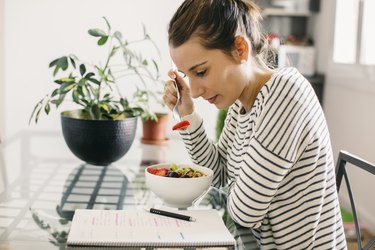 Person sitting at table with their brain breakfast of overnight oats with blueberries and walnuts looking at notepad