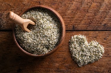 hemp heart seeds in a plate and spoon on a wooden background