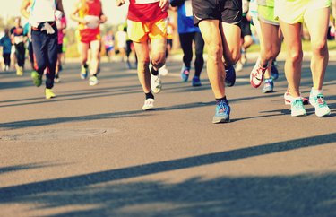 Unidentified marathon athletes legs running on city road