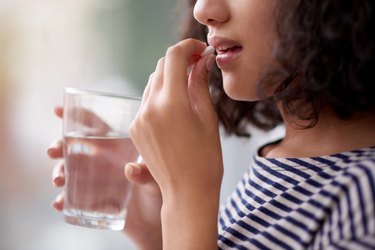 Close view of a woman taking a prednisone pill with water