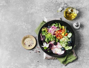 A top view of a fresh salad with dressing on the side, to help reduce hunger while dieting.