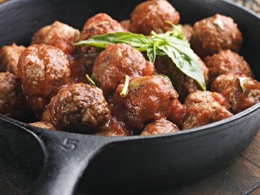 A cast iron pan full of meatballs in tomato sauce