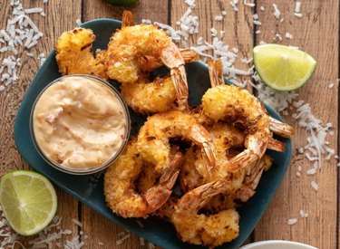 Air Fryer Coconut Shrimp on plate with orange dipping sauce and lime