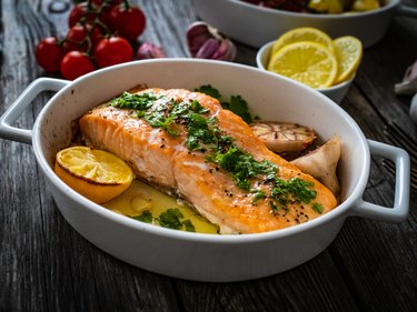 Roasted salmon steak, roasted potatoes and tomatoes on wooden table