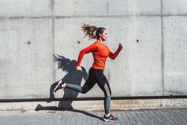 woman in red longsleeve and black leggings running outside