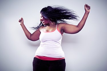 middle-aged woman wearing white tank and dancing