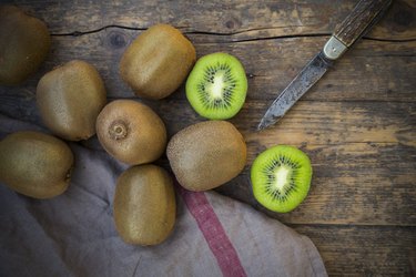 Kiwis (Actinidia deliciosa) and pocketknife on wooden table