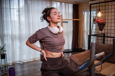 Person wearing a purple T-shirt on an exercise bike in a dimly lit room practicing cozy cardio.