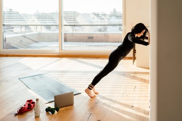 person with rheumatoid arthritis doing a wall push-up in living room at home