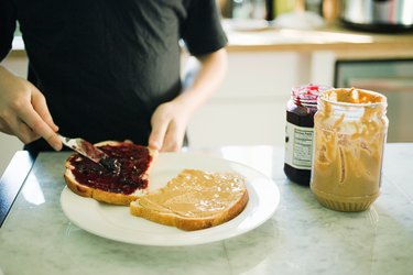 Close up of person making a peanut butter and jelly sandwich, wondering if peanut butter makes you poop