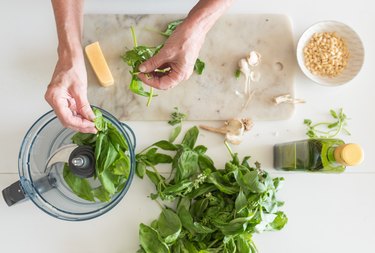 Woman's hands preparing basil for pesto from above