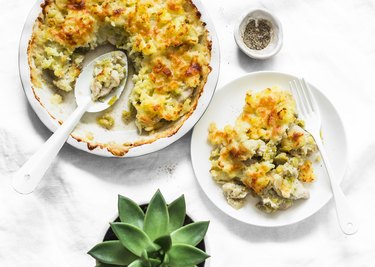 Creamy chicken breast, cauliflower, leek pie with crispy potato cheese topping on light background, top view