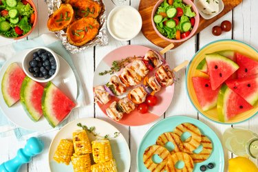 Summer BBQ or picnic food flat lay table scene over white wood