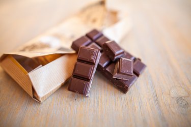 dark organic chocolate bar on a wooden table, broken up into squares