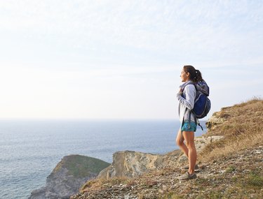 Hiker looking out toward sea from cliff top during a rucking workout