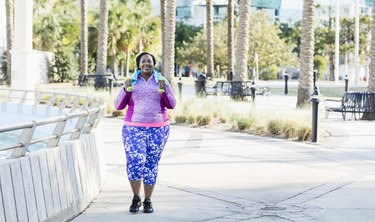 African American woman walking outside with hand weights, feeling hip popping