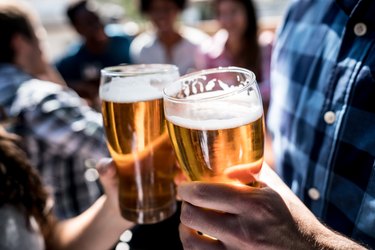 Close up of two people at a bar holding a beer and making a toast