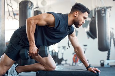 Person in navy blue shirt and shorts working out with dumbbells in gym