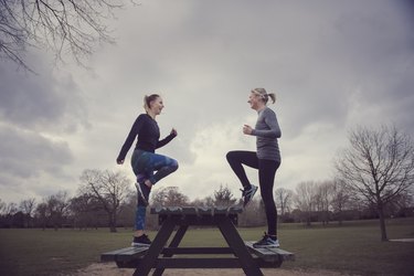 Full length side view of women doing step-ups on picnic bench