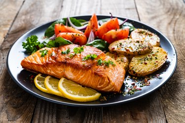 air fryer salmon steak, fried potatoes and vegetables on wooden background