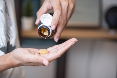 close view of a person pouring iron supplements into their hand from a small brown bottle