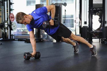 Man exercising in gym, doing renegade rows, to build muscle