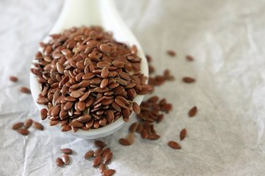 Close-up of flaxseeds in a ceramic spoon on white background