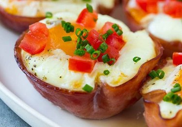 egg cups made inside a slice of ham topped with tomatoes and chives