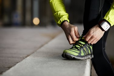 Person outside in workout clothes bending over to tie their shoe.