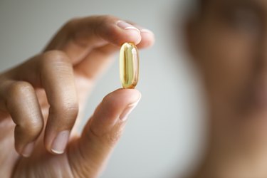 A woman holding a fish oil supplement capsule