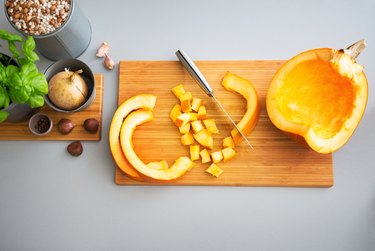 overhead photo of chopped raw pumpkin on a cutting board