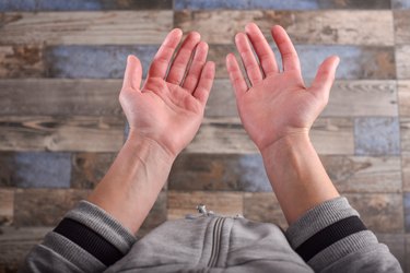 close view of a person holding out their hands, with their red palms facing up toward the camera, against a wooden backgroound