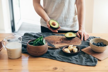 Young Woman cutting avocado for Healthy Smoothie For Breakfast